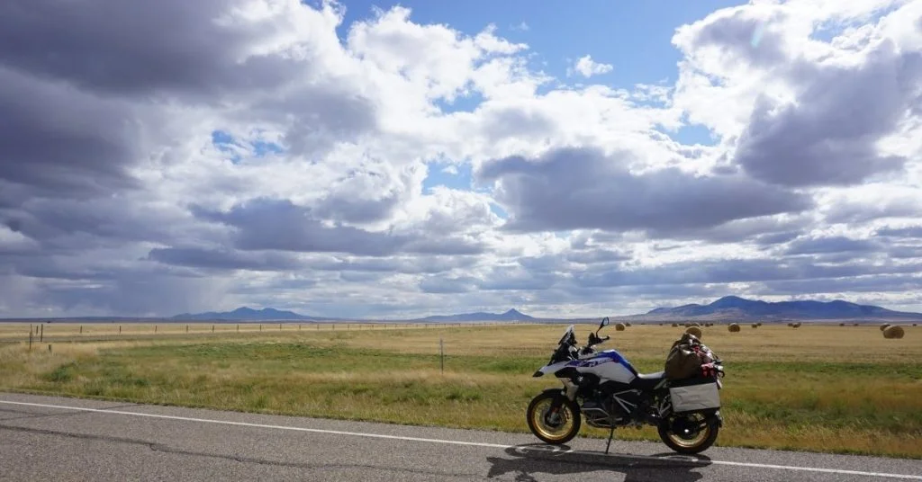 Motorcycle parked on the side of a road approaching a storm.